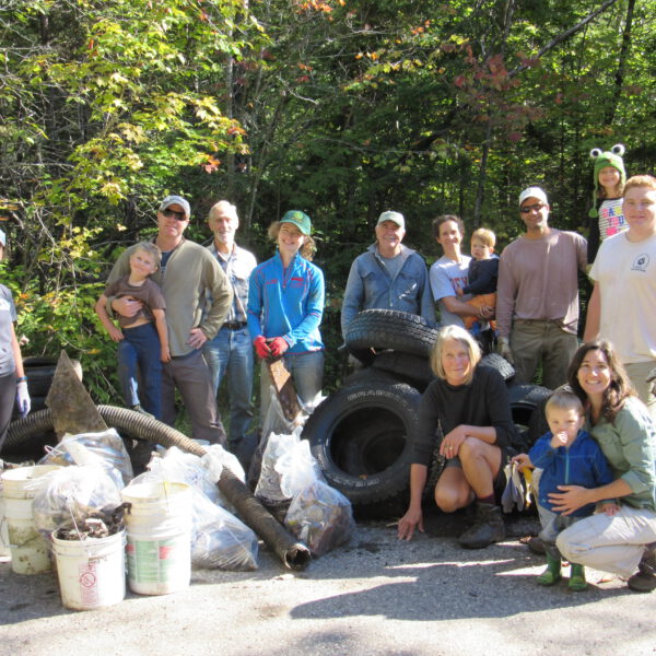 Volunteers smile after cleaning up trash and old tires from the river.