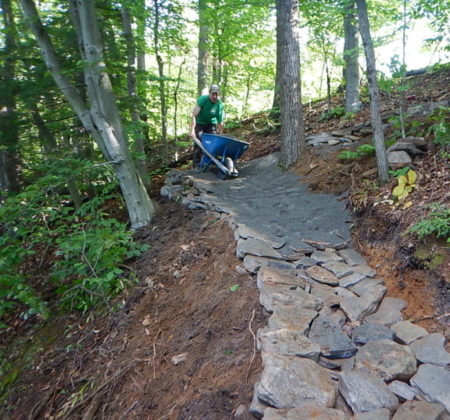 Gravel and stone trail work along a river access route.