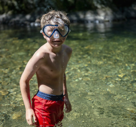 A kid jumps off some rocks into a Vermont swimming hole