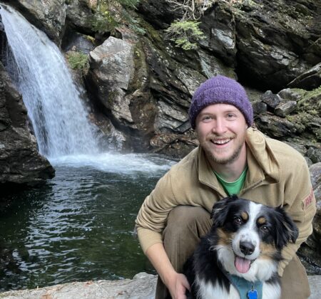 Remy Crettol with his dog in front of a waterfall.