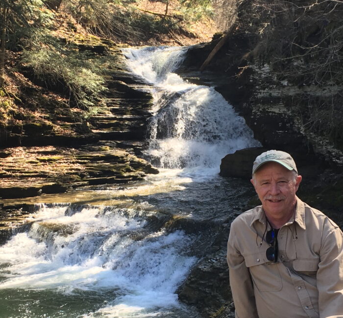 Mike Kline sits on a rock beside a flowing waterfall