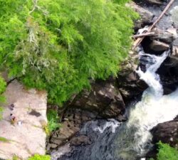 Person sitting on rocks above the Big Falls of the Missisquoi