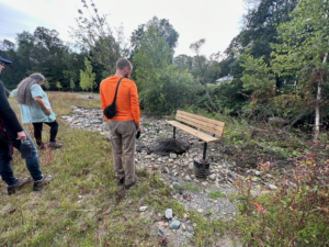Group looks at bench that lost sediment surrounding it so it is too tall to sit on