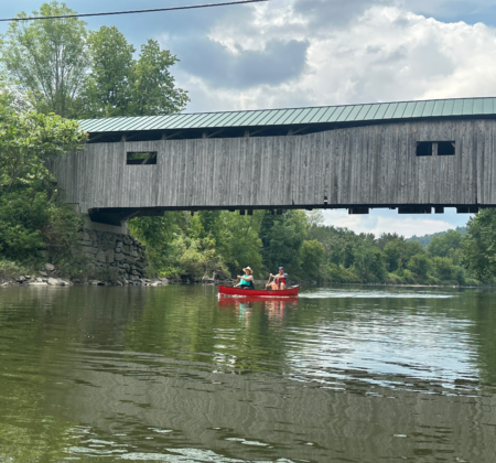 Paddlers canoe under Poland Covered Bridge in Cambridge, VT