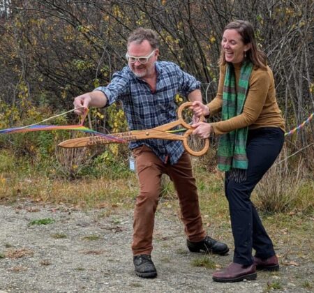 Erin De Vries and Brian Bannon with giant scissors for ribbon cutting