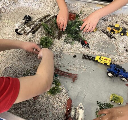 Kids hands playing in stream table.